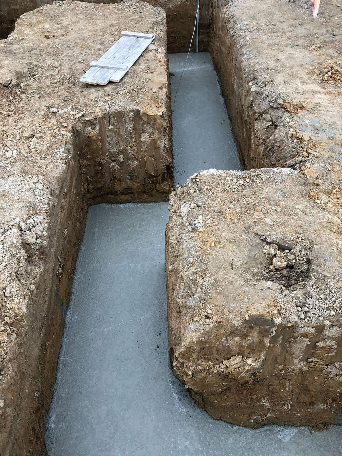 Výkop základových pasů s vylitým betonem na dně rýhy