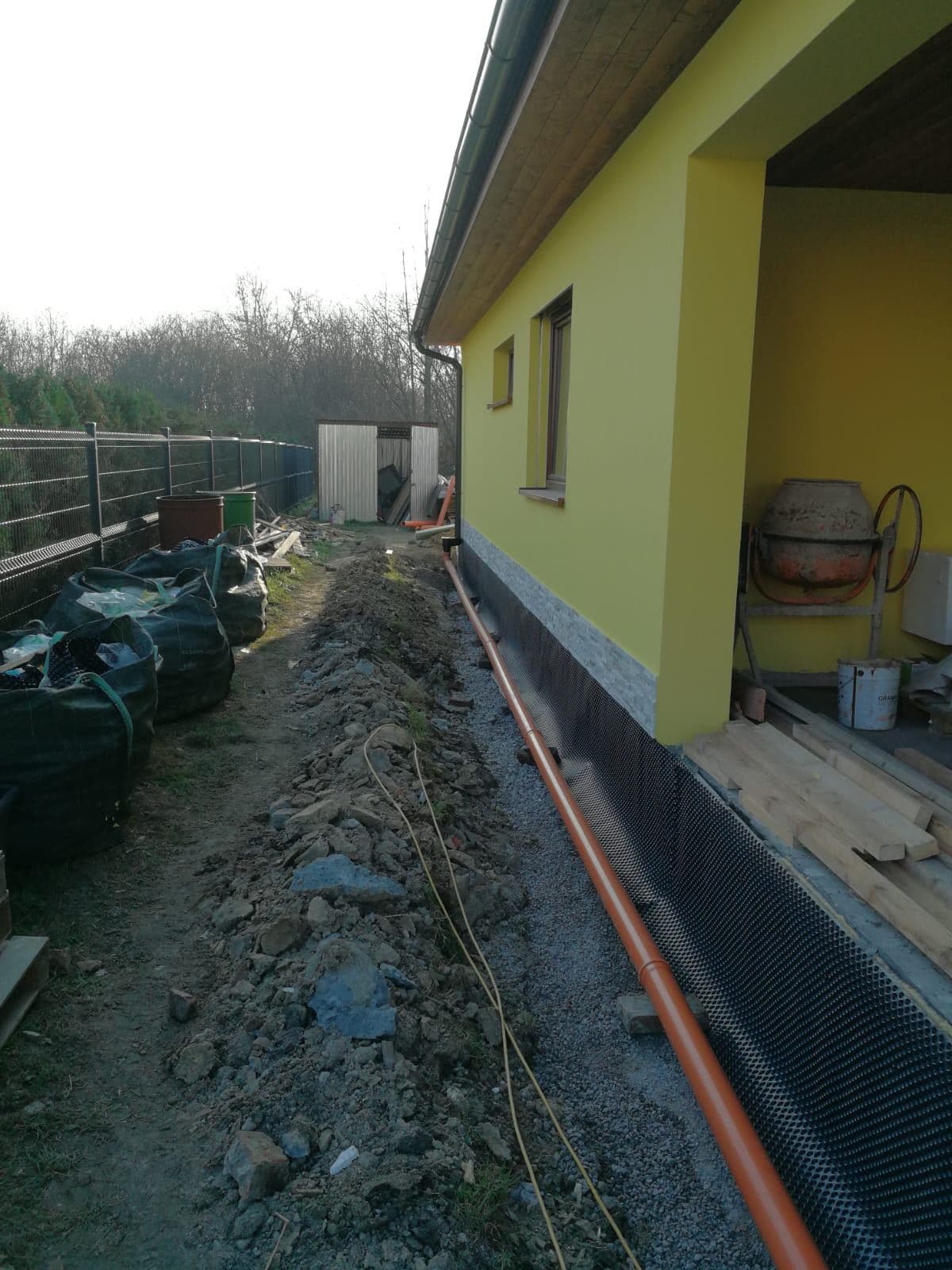 Drenáž a nopová fólie podél základů rozestavěného domu